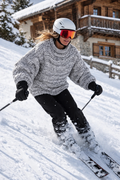 Jodie in Snow Storm skiing beside a rustic alpine chalet